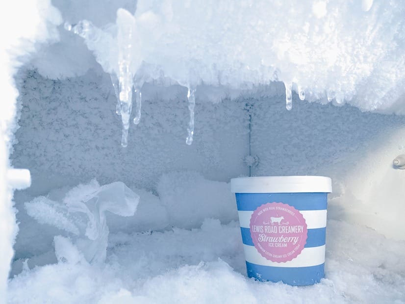A freezer full of ice crystals with a container of sorbet inside