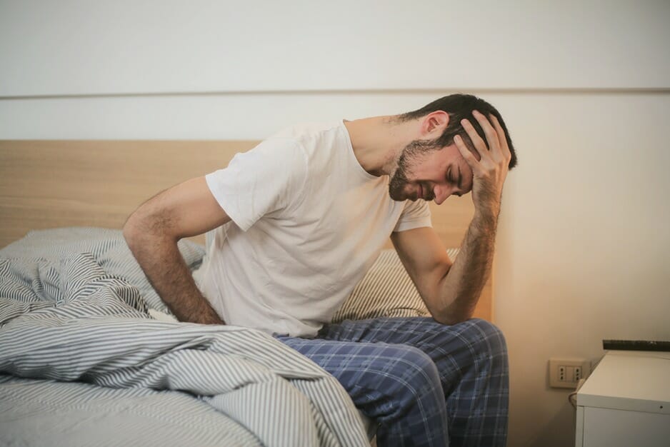 Man suffering from pain sitting on his bed